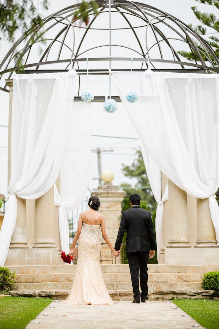 Mastering the First Impression: Your intriguing post title goes here A couple holding hands, walking towards an elegant outdoor wedding arch in Marsfield, NSW.